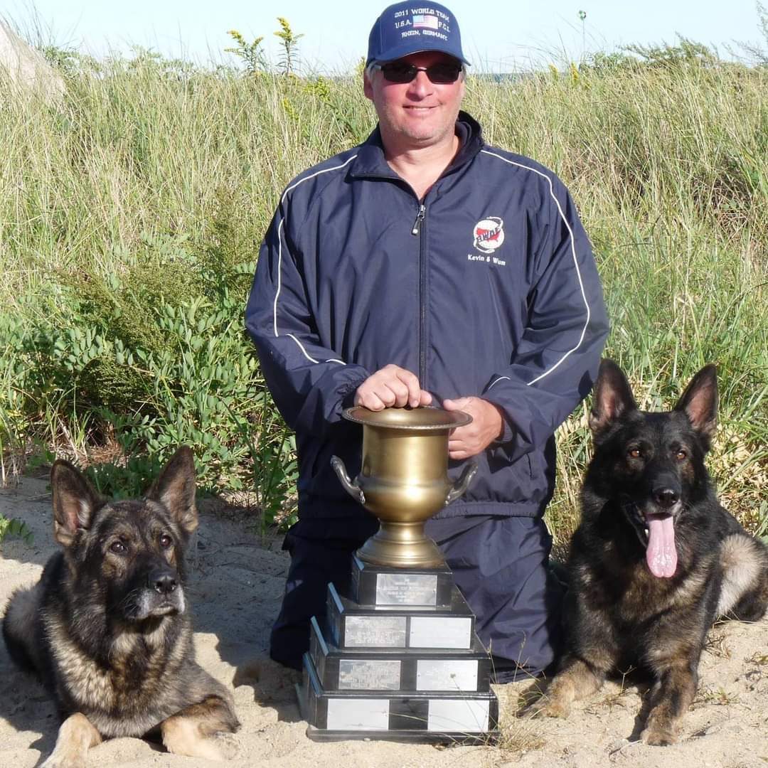 Kevin A. Lanouette with a competition trophy and two German Shepherds